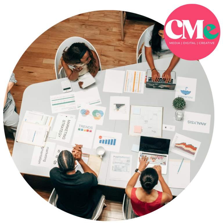 Team sat by the table with lots of papers on the table working on marketing