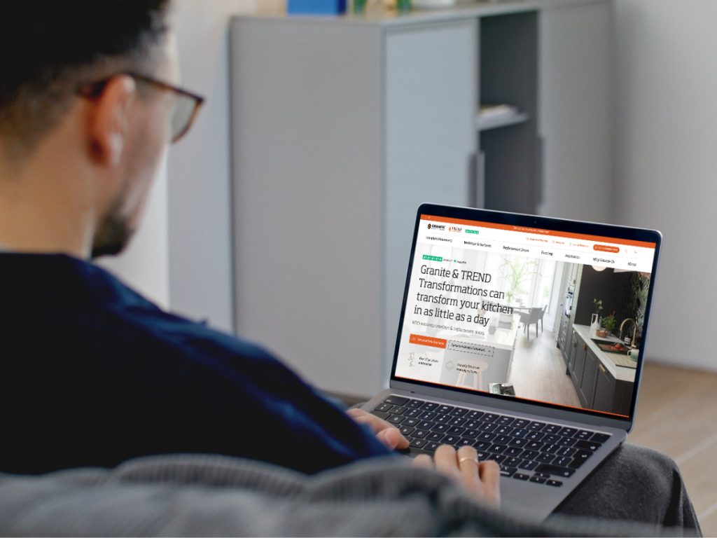 Male sitting on the sofa with laptop open on a Granit Transformations homepage