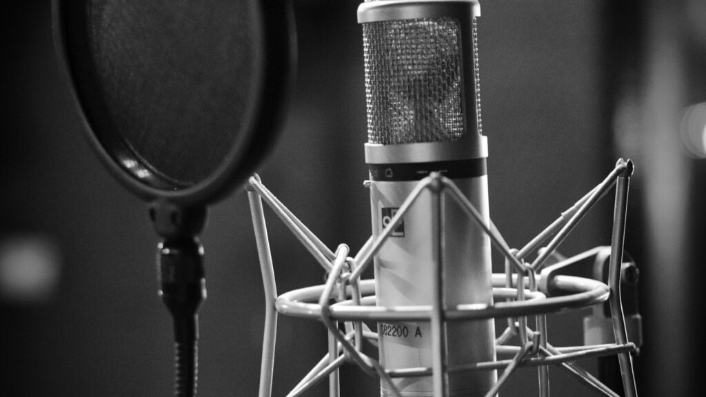 Condenser microphone with pop filter in a dark recording studio