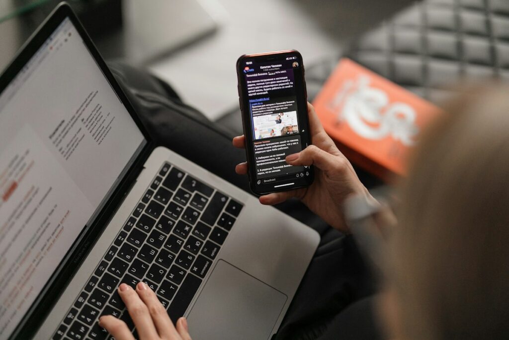 Woman on a sofa viewing content on a laptop and smartphone