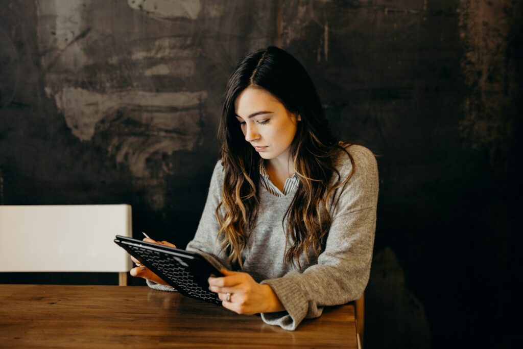 Woman reading an article on a tablet at a wooden table