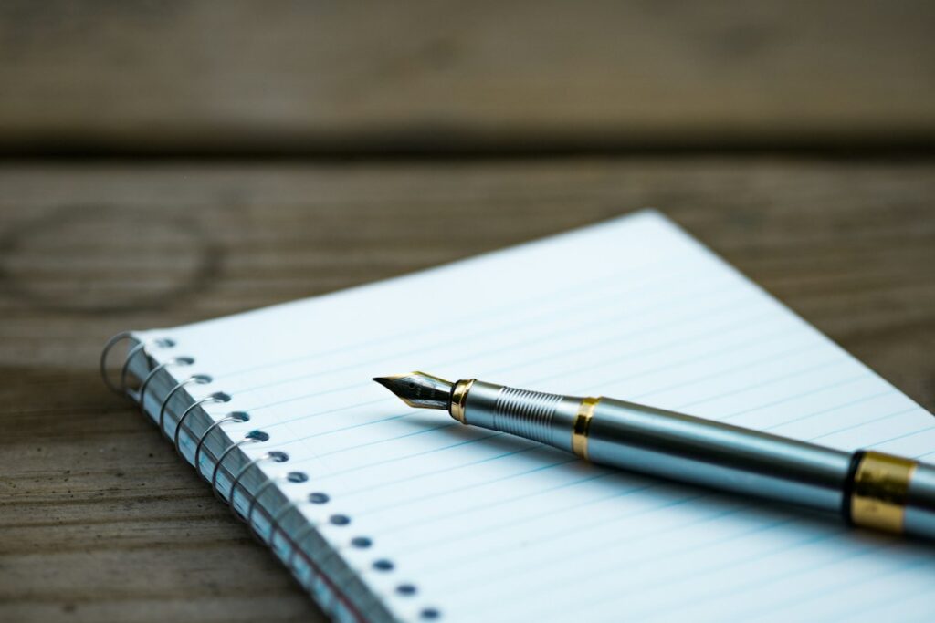Fountain pen resting on a notebook of handwritten drafts