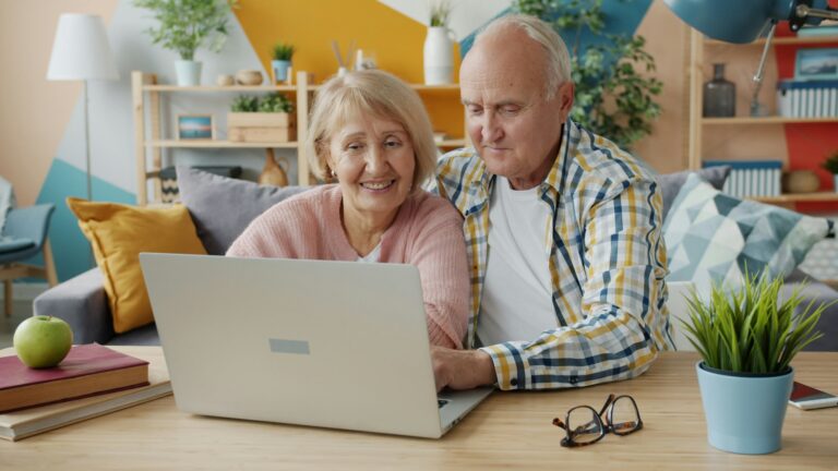 Smiling older couple looking at a laptop together at home